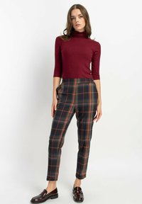 Burgundowy golf i spodnie w kratę w ciemnym szarym kolorze z czerwonymi i niebieskimi akcentami. Slim fit z bocznymi kieszeniami i ciemnymi mokasynami.