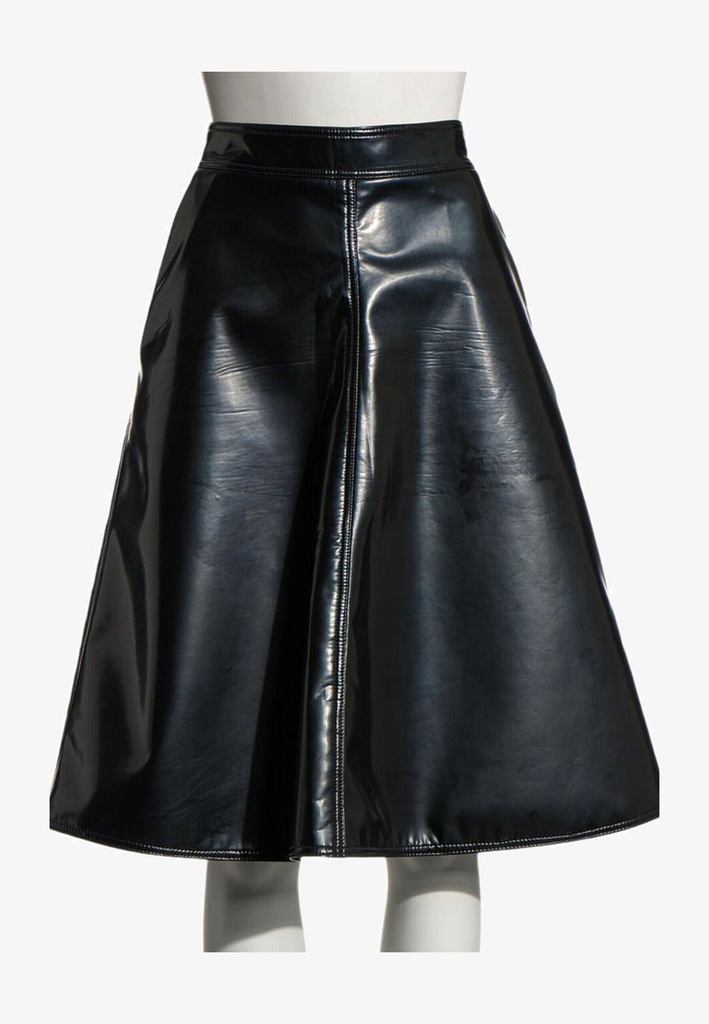 Jupe trapèze en similicuir noir brillant avec une couture verticale visible au centre, portée sur un mannequin avec un fond blanc.