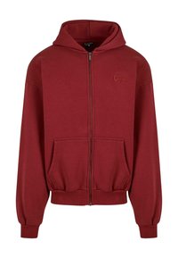 Red zip-up hoodie made of soft fabric, featuring a large hood, front pockets, ribbed cuffs, and a discreet logo on the chest.