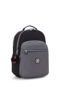 Rucksack aus schwarzem und grauem Material, mit einer vorderen Reißverschlusstasche, runder Logo-Patch und einem kleinen Affenschlüsselanhänger, der am Reißverschluss befestigt ist.
