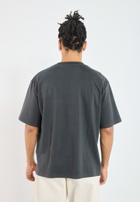 Dark gray cotton t-shirt with short sleeves, crew neck, and a relaxed fit. The fabric has a smooth texture with a slight stretch.