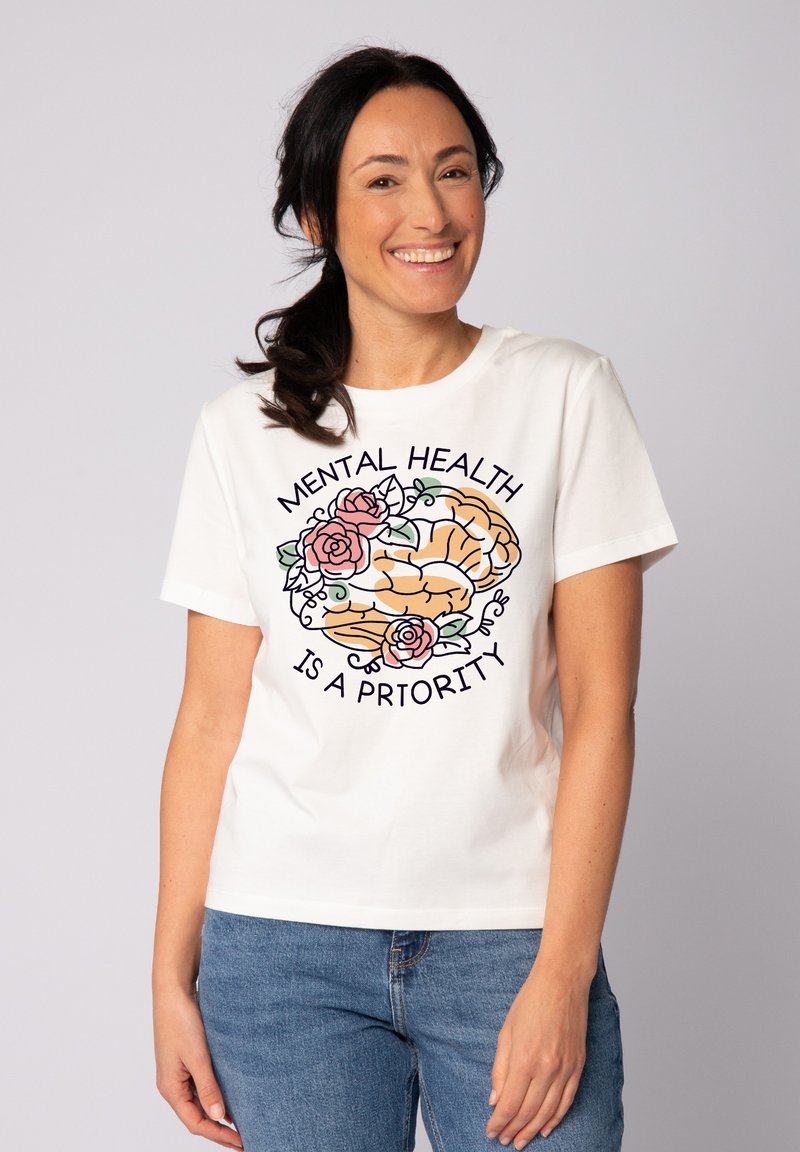 T-shirt en coton blanc avec un graphique d'un cerveau entouré de roses, portant le texte "LA SANTÉ MENTALE EST UNE PRIORITÉ" en noir.