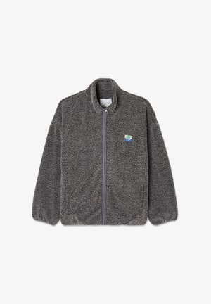 Graue Fleecejacke mit durchgehendem Reißverschluss, hohem Kragen und strukturiertem Material. Ausgestattet mit einem kleinen, mehrfarbigen Logopatch auf der linken Brust.
