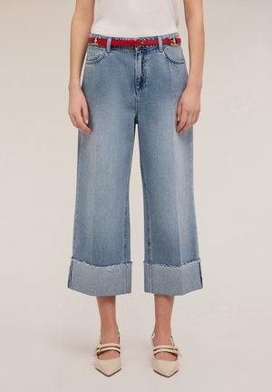 Light blue wide-leg jeans with frayed hem, paired with a red belt featuring a gold buckle, worn with nude heeled shoes.