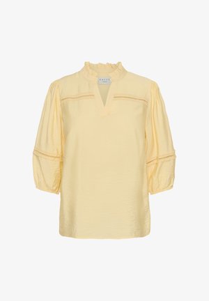 Žltá blúzka s volánovým golierom, výstrihom do V, nafúknutými trojštvrťovými rukávmi a čipkovými detailami na hrudi a rukávoch.