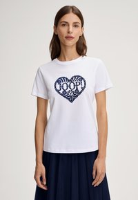 Wit katoenen T-shirt met een marineblauw hartontwerp met decoratieve elementen en de tekst "JOOP!" in het midden, ronde hals, korte mouwen.
