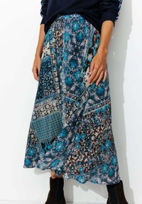 Jupe maxi multicolore, bleu et marron, avec des motifs floraux et géométriques, dotée d'une taille élastique et d'un tissu fluide.