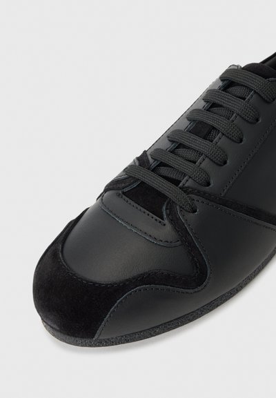 Black sneaker featuring a mix of smooth leather and suede, streamlined design, round toe, and flat laces with textured accents.