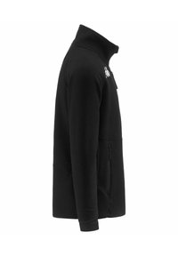 Giacca in pile nera con colletto alto. Presenta una tasca laterale con zip e un logo bianco sul petto. Tessuto morbido e texturizzato.