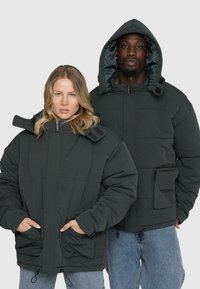 Mørkegrå polstret jakker lavet af quiltet stof, med hætte, forlommer og justerbare snore i kanten.