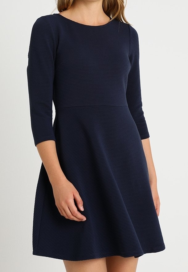 Robe bleu marine côtelée avec un corsage ajusté et une jupe évasée. Comprend des manches trois-quarts et un col rond.