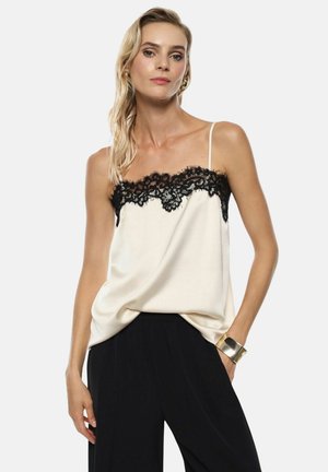 Camisola in satin crema con bordo in pizzo nero sul collo. Presenta spalline sottili e regolabili e una silhouette ampia e fluida.