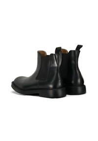 Bottes Chelsea en cuir noir avec panneaux latéraux élastiques, bouts arrondis et languettes de tirage. Texture lisse avec une semelle basse et solide.