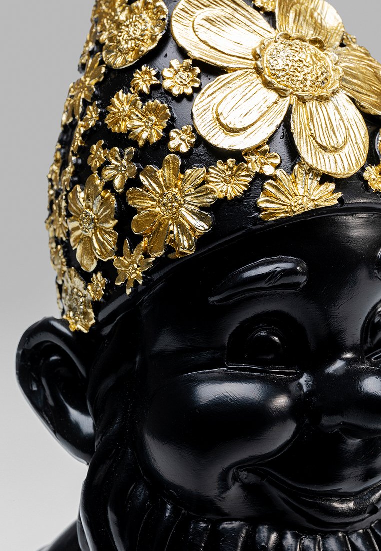Un nain de jardin noir avec un visage texturé, orné de fleurs dorées intriquées sur le chapeau, créant un contraste et des détails vifs.