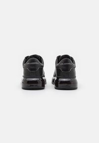 Zwarte sneakers met een glad leren bovenwerk, glanzende ronde zool en contrasterende accenten. Bevat een reliëflogo op de hak.