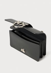 Zwarte leren tas met zilverkleurige hardware, voorzien van een unieke sluiting in de vorm van een vogel, een ritscompartiment en een gestructureerde vorm.