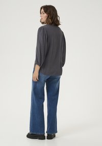 Grijze blouse met textuurpunten,Gathered mouwen en een relaxte pasvorm, gecombineerd met wijde blauwe jeans en zwarte plateau laarzen.