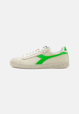 Sneaker in pelle bianca con un brillante logo swoosh verde, suola in gomma texturizzata e design tradizionale con lacci e perforazioni.