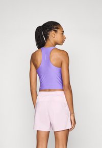 Lilla ermeløs treningstopp med rund hals, kombinert med lyserøde shorts. Inkluderer perforerte detaljer og en tettsittende design.