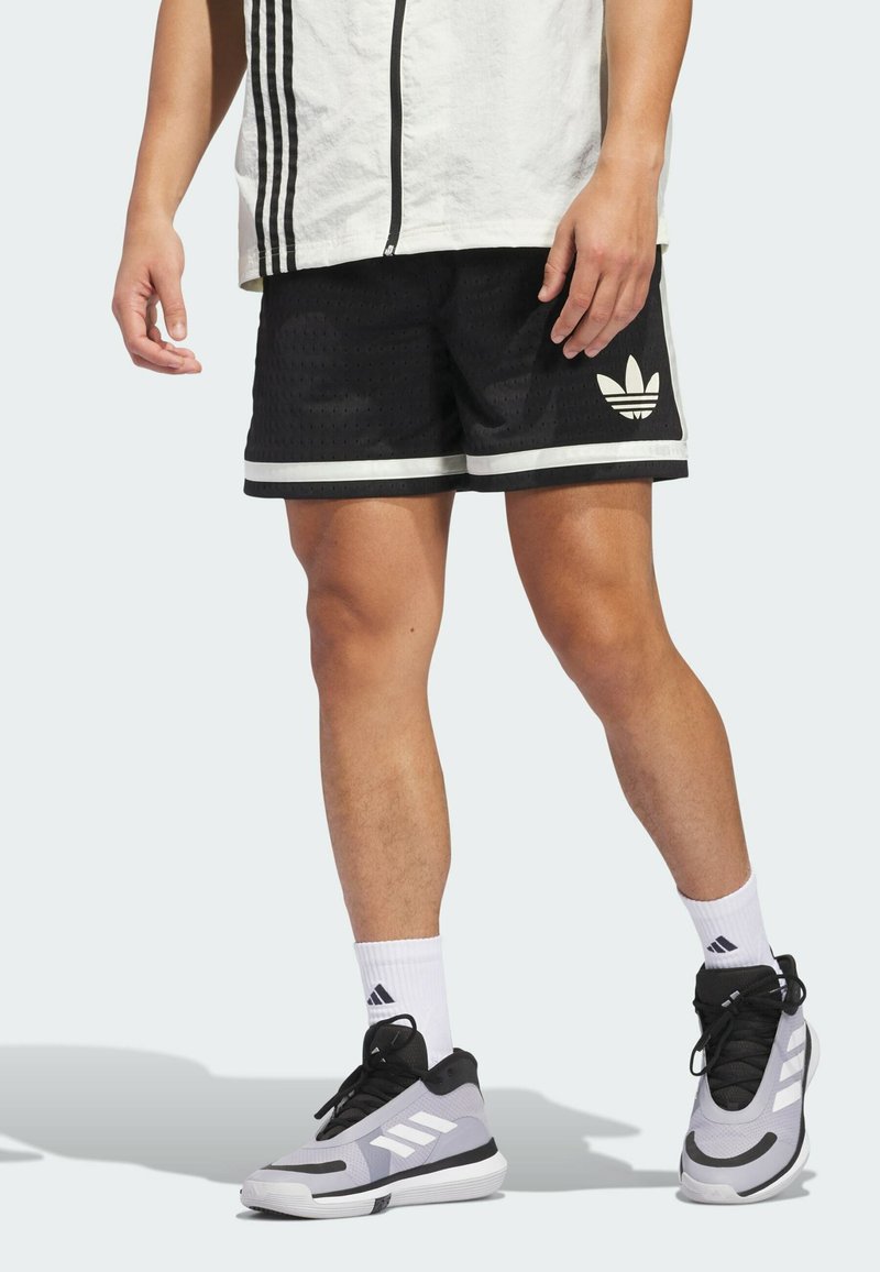 Black athletic shorts with a textured pattern, white stripes on the hem, and an Adidas logo. Paired with gray and black sneakers.
