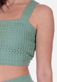 Myntegrøn cropped top med et tekstureret, bølget strikdesign. Har brede skulderstropper og en logodetail nær kanten. Blødt stoffinish.
