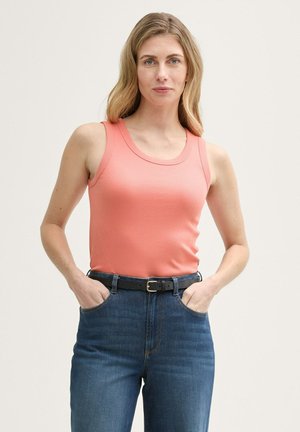 Top en corail ajusté avec un col rond et des bretelles larges, associé à un jean bleu taille haute et une ceinture noire.