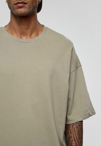 Khaki katoenen t-shirt met een relaxte pasvorm, ronde halslijn en korte mouwen. Heeft een gladde textuur en minimale stikdetails.