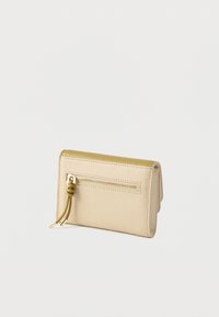 Bežinė ir alyvuogių žalios tekstūruotos odos piniginė su auksine užtrauktuko kišene ir surištu užtrauktuko traukikliu ant balto fono.