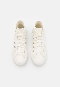 Par de zapatillas altas de lona blancas con cordones blancos y suelas de goma, exhibidas una al lado de la otra sobre un fondo blanco plano.