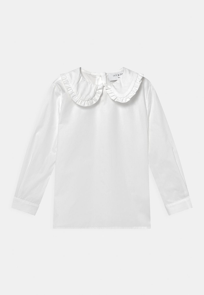 Blouse blanche à manches longues avec un col à volants, en tissu lisse. Dotée d'une fermeture à boutons à l'arrière et de poignets structurés.