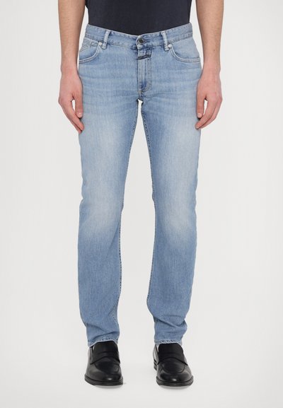 Jean en denim bleu clair avec une coupe droite, fermeture à bouton en métal, poches avant et décoloration subtile sur le tissu.