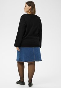 Fekete kötött pulóver, kék farmer A-vonalú szoknya, fekete harisnya és fekete lakkcipő. A pulóver laza szabású; a szoknya szegélyvonal varrással rendelkezik.