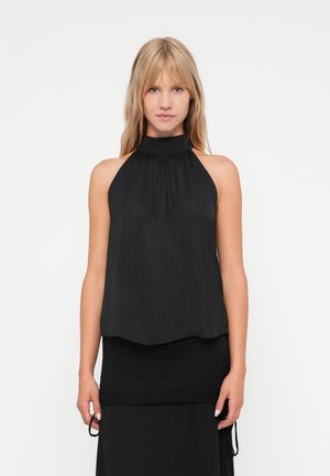 Top preto de halter feito de tecido leve, com decote franzido e ajuste fluido, combinado com uma saia preta justa.