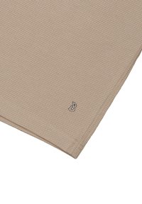 Beżowa koszula z ryflowanej tkaniny z małym srebrnym logo na dolnym brzegu. Posiada fakturowaną powierzchnię i starannie obszyte krawędzie.