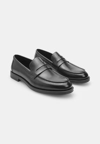 Mocassins en cuir noir avec une finition lisse, dotés d'une sangle décorative sur le devant, de bouts arrondis et de semelles en caoutchouc plates.