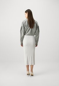 Fustă midi texturată alba cu nervuri, asortată cu o cămașă cu dungi verticale alb-negru. Modelul poartă pantofi cu toc nude.