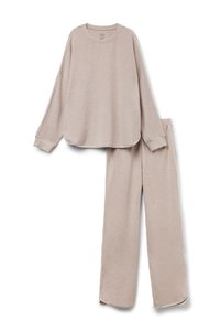 Lichtbeige loungewear-set met een long-sleeve top met een afgeronde zoom en bijpassende losse broek met zijsplitten en elastische tailleband.