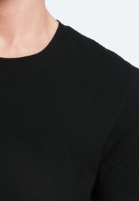 Black crew-neck t-shirt with short sleeves. Made from soft cotton fabric, featuring a smooth texture and no visible logos or patterns.
