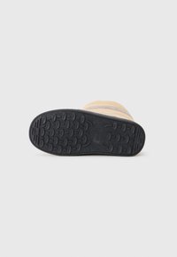 Bota amarela com uma sola de borracha preta texturizada, apresentando padrões de tração irregulares e uma parte superior lisa. Detalhe de costura visível.