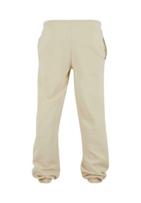 Beige bomulds joggerbukser med elastisk talje, sidelommer og elastiske manchetter ved anklerne for en afslappet pasform. Glat tekstur.