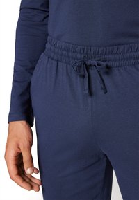 Navy blue joggers featuring an elastic waistband with a drawstring, made from soft fabric, showing a smooth texture and fit.