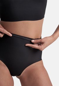 Mutande nere a vita alta con una texture liscia e una cintura elastica. Il design è minimalista, adatto per l'uso quotidiano.