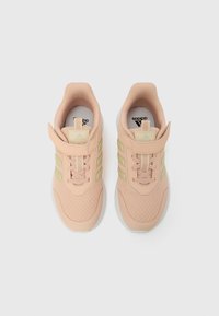 Adidași roz deschis cu partea superioară din plasă texturată, trei dungi verzi și guler căptușit la gleznă. Include o bandă cu Velcro pentru închidere.