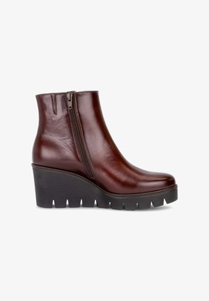 Bottine en cuir marron foncé avec fermeture éclair sur le côté et semelle compensée noire épaisse à crampons profonds, vue du côté extérieur.