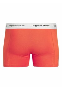 Orange bomullsboxer med vit midja som har svart text "Originals Studio." Slät textur och figurnära passform.