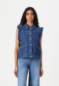 Denim vest med krage, volanger ved ermet, frontlommer og knappestengning. Tøyet er en mellomblå farge med et klassisk design.