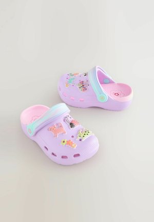 Violetit puukengät, joissa on vaaleanpunainen sisusta ja koristeellisia yksityiskohtia, kuten perhosia ja eläimiä. Varustettu hihnalla ja tuuletusaukoilla hengittävyyttä varten.