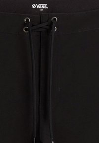 Shorts noirs avec une fermeture à cordon, œillets en métal et logo Vans sur la ceinture. Le matériau semble lisse avec une texture minimale.