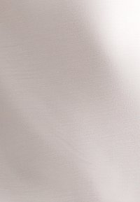 Zacht lichtbeige stof met een gladde textuur en subtiele glans, met een verfijn patroon en lichte diagonale lijnen.