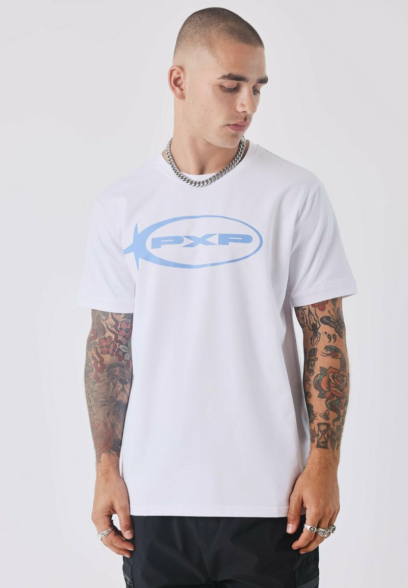 Camiseta de algodón blanca con un logo "PXP" en azul claro en el frente. Mangas cortas, cuello redondo y corte relajado con tatuajes visibles en los brazos.